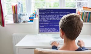 Boy coding on his laptop at home.